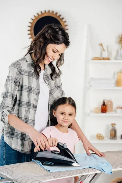 Mãe em camisa cinza e filha de engomar em casa — Fotografia de Stock