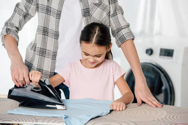 Mother and daughter in pink t-shirt ironing in laundry room — Stock Photo