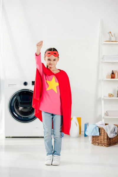 Child in red homemade superhero suit in laundry room — Stock Photo