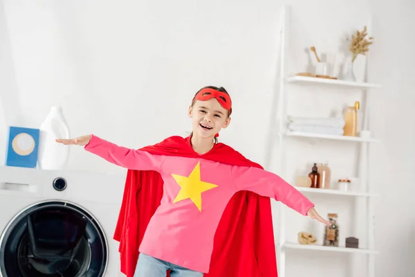 Criança em terno caseiro vermelho com sinal de estrela se divertindo na lavanderia — Fotografia de Stock