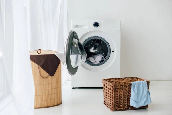 Geöffnete Waschmaschine und braune Körbe in der Waschküche — Stockfoto