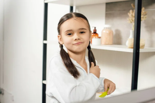 Foyer sélectif de mignon enfant en peignoir blanc peignage dans la salle de bain — Photo de stock