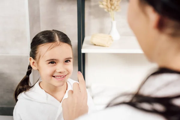 Selective focus of daughter smiling to mother in bathroom — Stock Photo