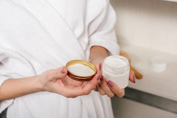 Vue recadrée de femme tenant récipient avec crème cosmétique dans la salle de bain — Photo de stock