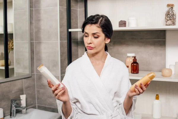 Femme tenant des bouteilles avec gel douche dans la salle de bain — Photo de stock