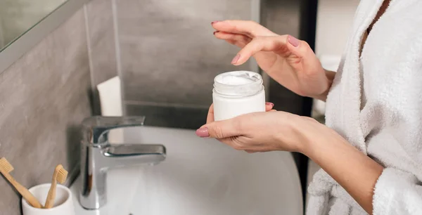 Panoramic shot of woman holding container with lotion in bathroom — Stock Photo