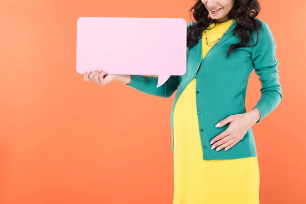 Cropped view of smiling pregnant woman holding speech bubble isolated on orange — Stock Photo