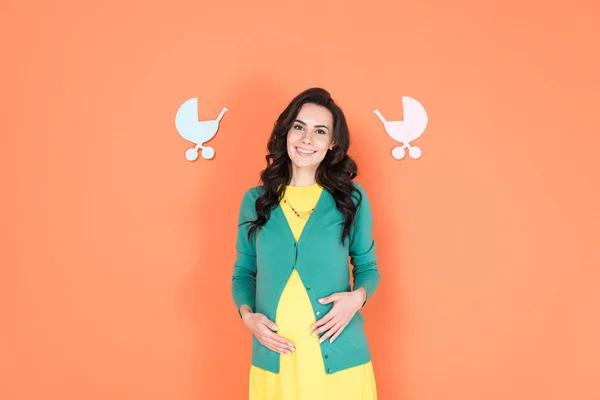 Glücklich schwangere junge Frau berührt Bauch auf orangefarbenem Hintergrund — Stockfoto