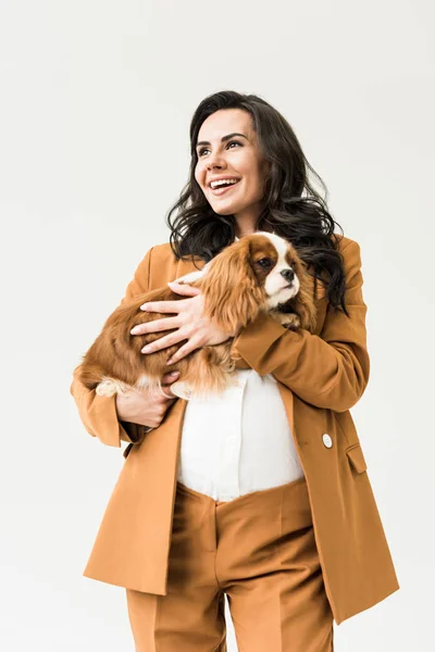 Emocionada mujer embarazada en traje sosteniendo perro aislado en blanco - foto de stock