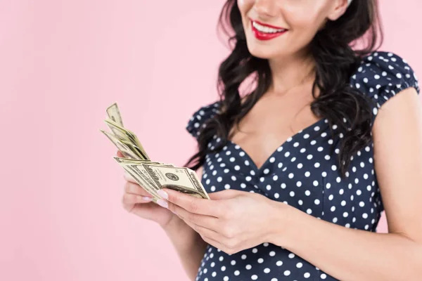 Обрізаний вид щасливої вагітної жінки, що тримає доларові банкноти ізольовані на рожевому — стокове фото