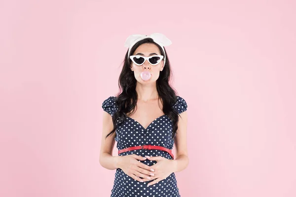 Bruna donna incinta masticare gomma da masticare e toccare pancia isolato su rosa — Foto stock