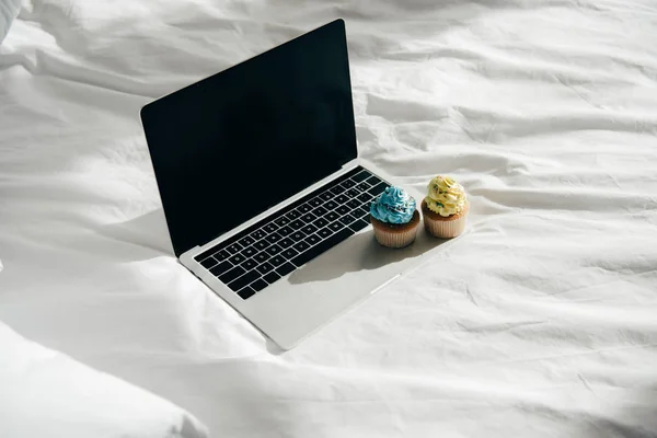 Süße und leckere Cupcakes auf Laptop mit leerem Bildschirm — Stockfoto
