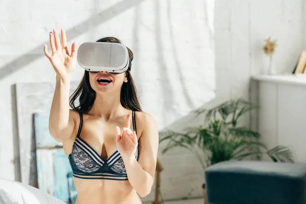 Femme brune joyeuse en sous-vêtements portant un casque de réalité virtuelle — Photo de stock