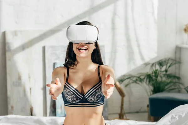 Счастливая брюнетка в нижнем белье в наушниках виртуальной реальности — стоковое фото