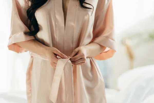 Cropped view of woman untying silk robe at home — Stock Photo