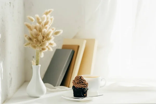 Chatons de saule dans un vase près de cupcake, tasse de café et livres — Photo de stock