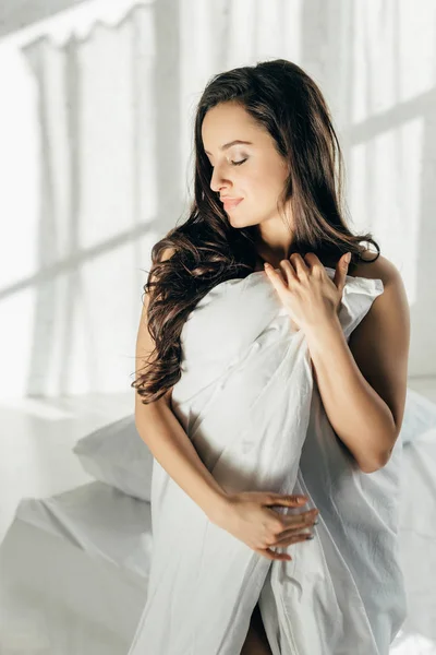 Sensual brunette naked woman wrapped in blanket standing with closed eyes — Stock Photo