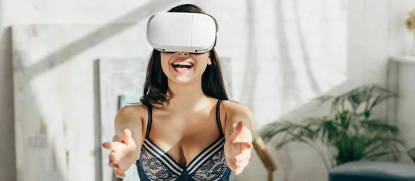 Panoramic shot of happy brunette woman in underwear wearing virtual reality headset — Stock Photo