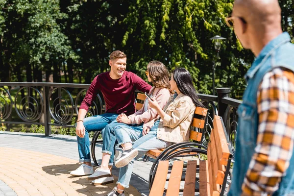 Vista trasera del hombre afroamericano mirando a amigos alegres en el parque - foto de stock