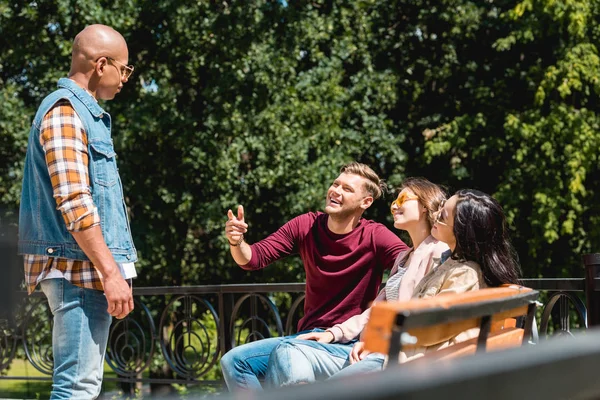 Smiling young man pointing with finger at african american friend in park — Stock Photo