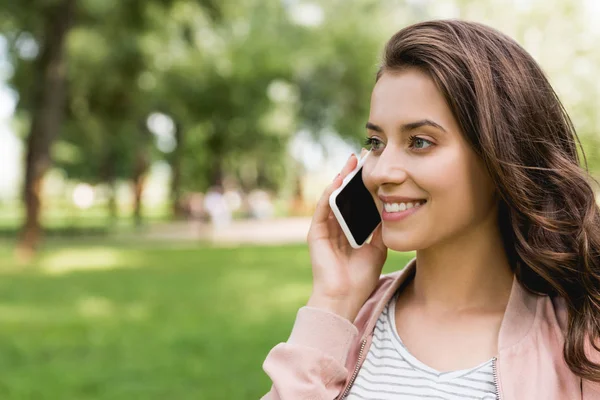 Attractive girl talking on smartphone in park — Stock Photo