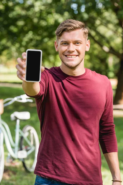 Enfoque selectivo del hombre feliz sosteniendo el teléfono inteligente con pantalla en blanco - foto de stock
