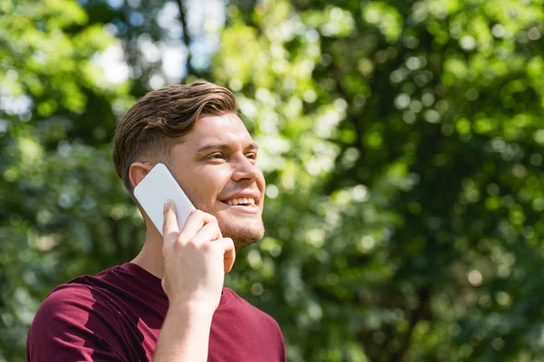 Jovem feliz falando no smartphone no parque — Fotografia de Stock