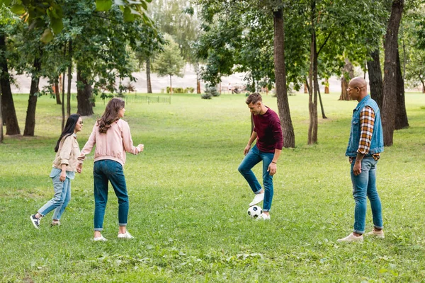 Alegre grupo multicultural de amigos jugando al fútbol en el parque - foto de stock