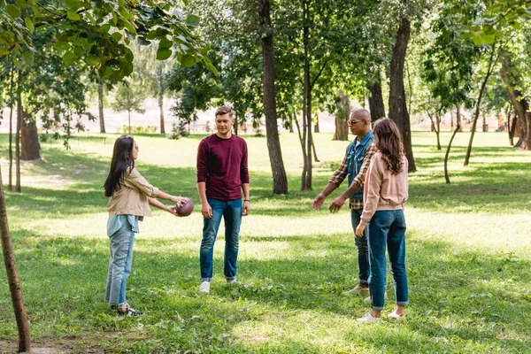 Cheerful multicultural group of friends playing american football in park — Stock Photo