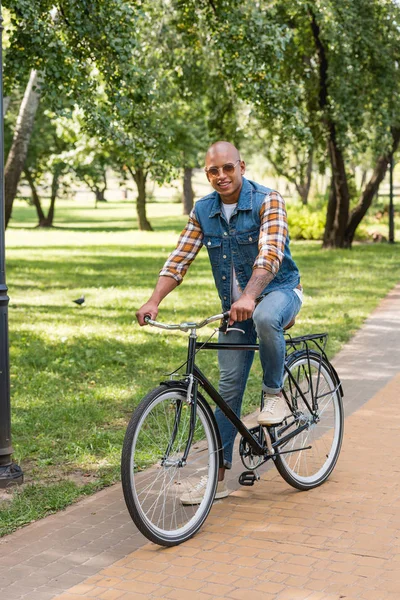 Homem americano africano alegre em óculos de sol andar de bicicleta — Fotografia de Stock