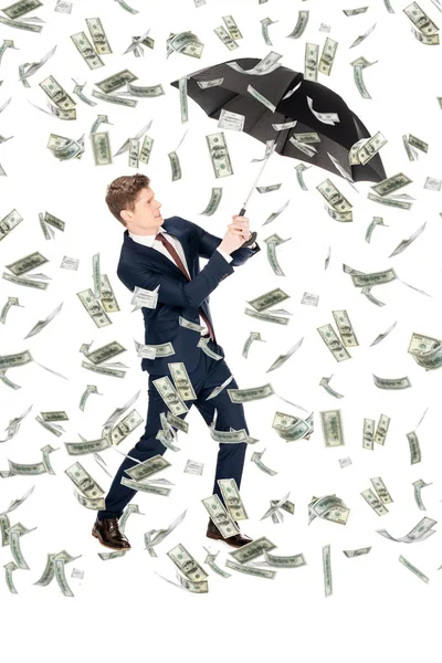 Successful businessman in suit holding umbrella under money rain on white background — Stock Photo