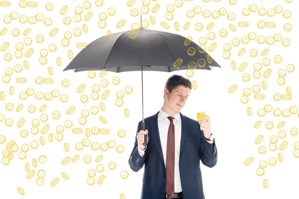 Успішний бізнесмен у костюмі, що тримає парасольку та жовтий скарбничку під монетами дощ на білому тлі — стокове фото
