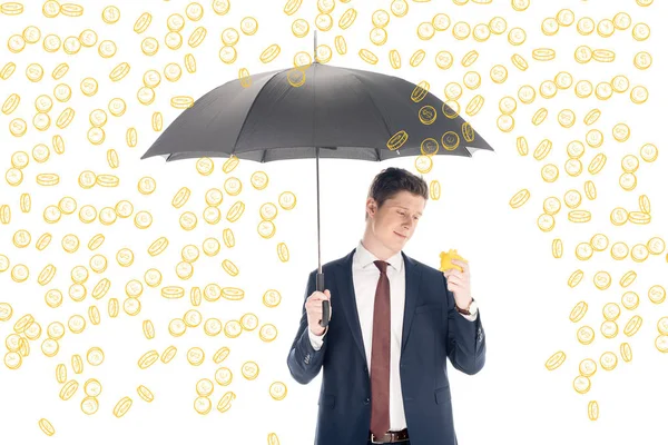 Successful businessman in suit holding umbrella and yellow piggy bank under coins rain on white background — Stock Photo