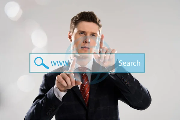 Handsome businessman in suit pointing with fingers at search bar illustration in front — Stock Photo