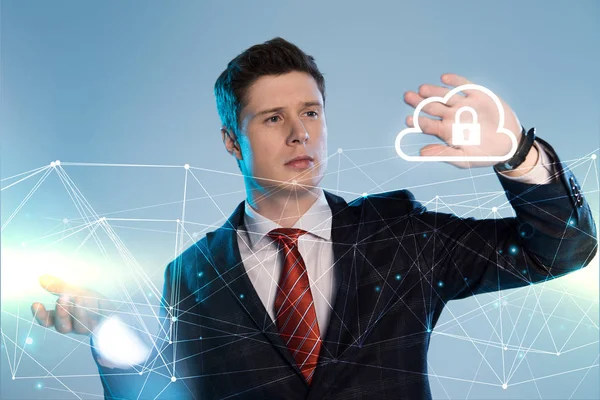 Schöner Geschäftsmann im Anzug zeigt auf Netzwerk und Lock-in-Cloud-Illustration vor blauem Hintergrund — Stockfoto