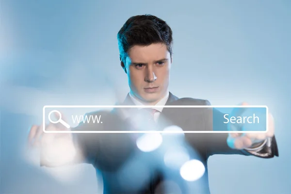 Confident businessman in suit pointing at search bar illustration in front on blue background — Stock Photo