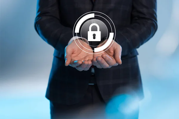 Partial view of businessman with outstretched hands and internet security icon above on blue background — Stock Photo