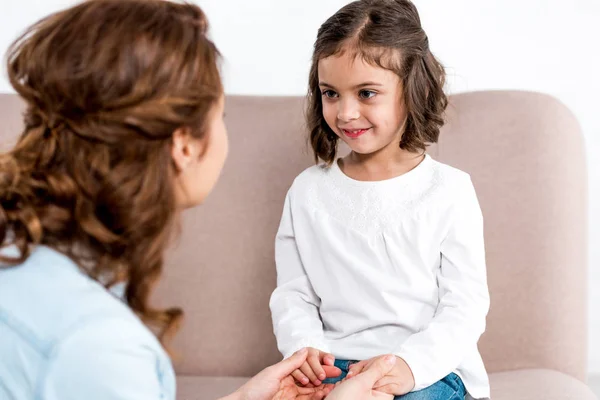 Mother and daughter holding hands and looking at each other on white — Stock Photo