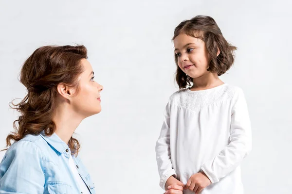 Lockige Mutter und Tochter schauen einander isoliert auf weißem Grund an — Stockfoto