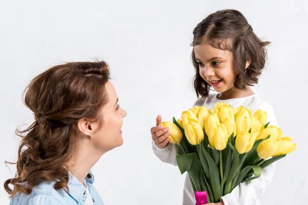 Smiling kid presenting yellow tulips to mother isolated on white — Stock Photo