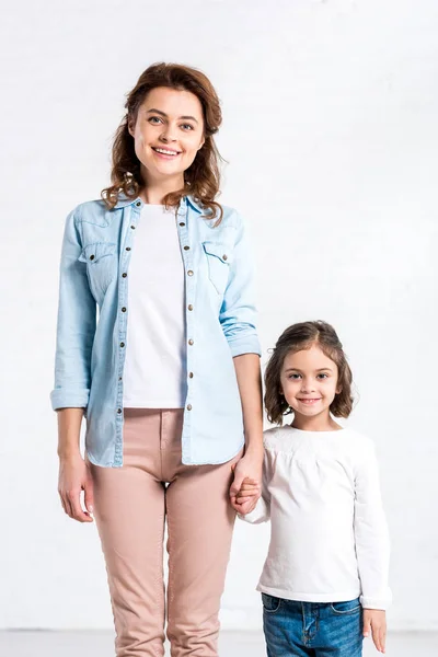 Lächelnde Mutter und Tochter halten Händchen auf weißem Grund — Stockfoto