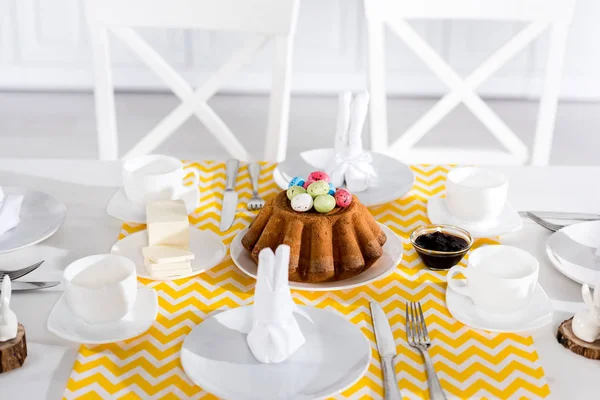 Bolo de Páscoa com ovos pintados e louças na mesa — Fotografia de Stock