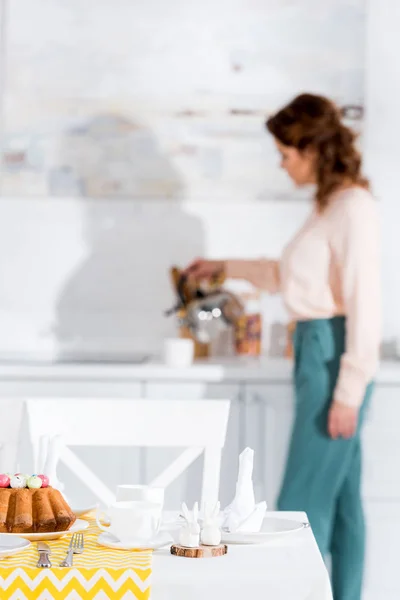 Curly woman with kettle and served table on foreground — Stock Photo