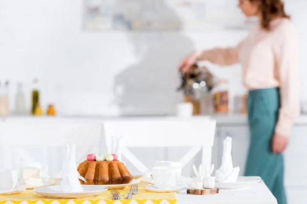 Mesa servida con pastel de Pascua, vajilla y servilletas en la cocina - foto de stock