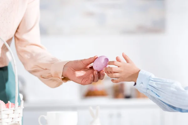 Частичное представление женщины, дающей окрашенное пасхальное яйцо ребенку — стоковое фото