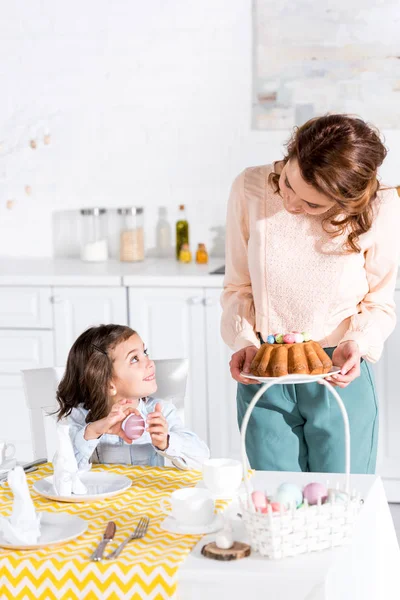 Madre e hija mirándose mientras sirven mesa para pascua - foto de stock