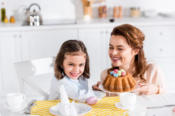 Mère et fille riantes servant table avec Pâques dans la cuisine — Photo de stock