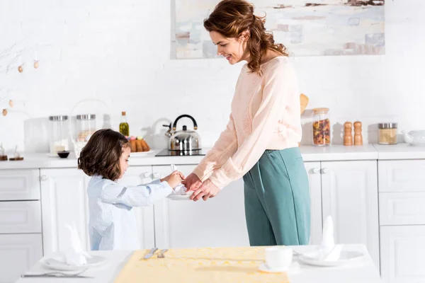 Mãe e filha pequena dobrar guardanapos enquanto está na cozinha — Fotografia de Stock