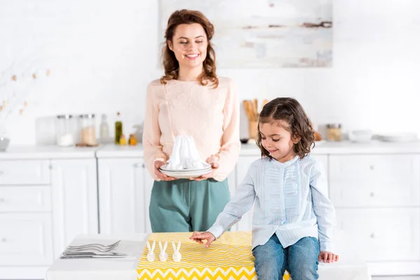 Smiling happy mother and daughter serving table in kitchen — Stock Photo