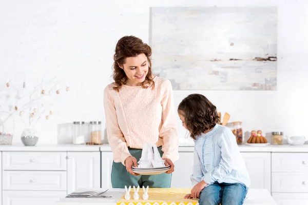 Усміхнена мати показує складені серветки дочці на кухні — стокове фото